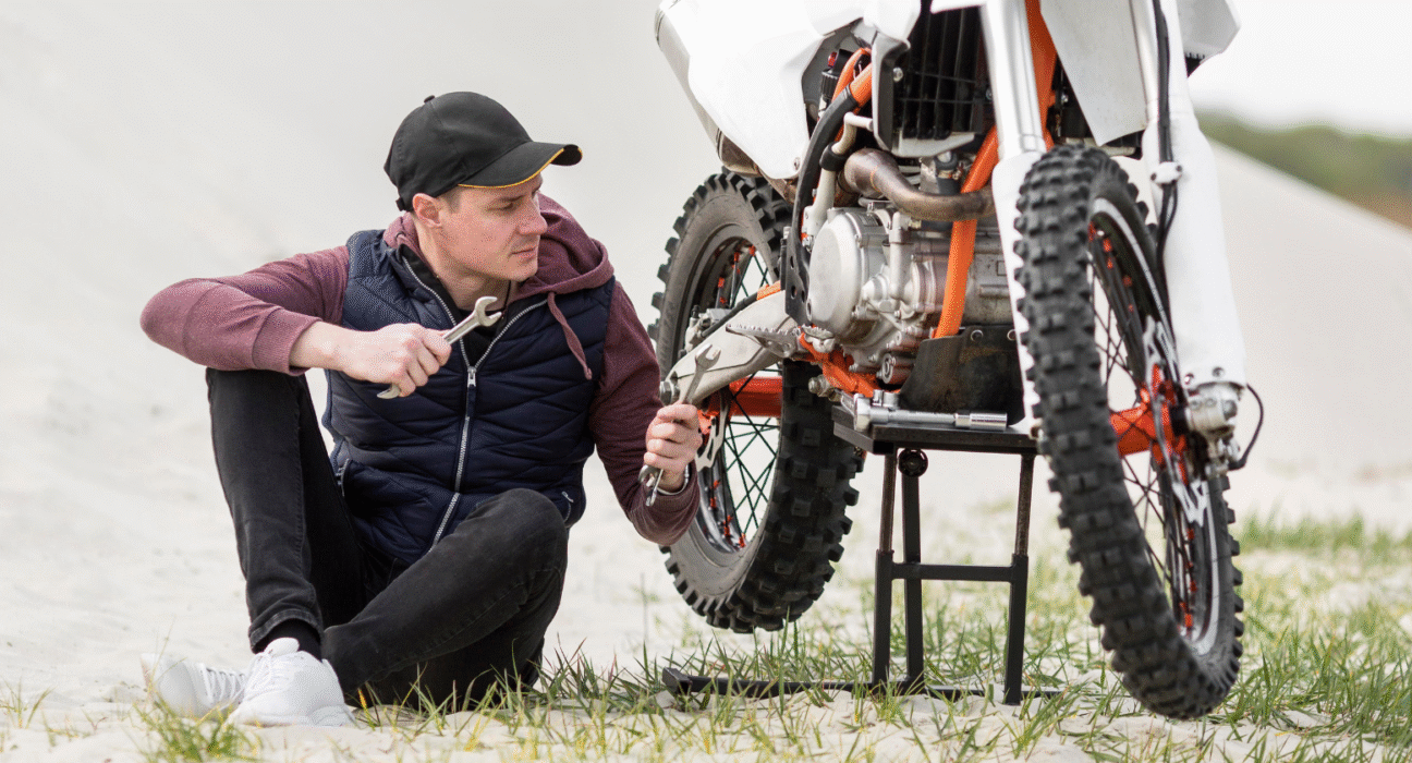 Frustrated rider sitting beside a motorcycle with tools trying to fix power loss issue