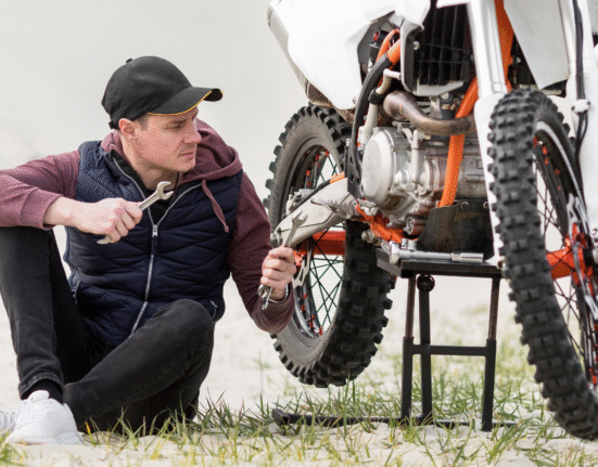 Frustrated rider sitting beside a motorcycle with tools trying to fix power loss issue